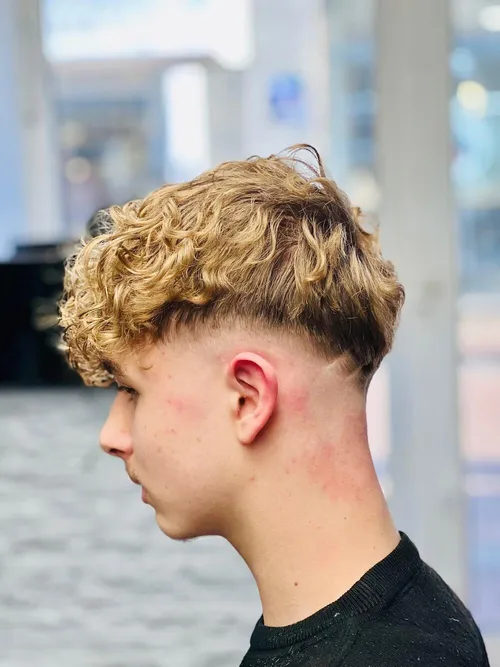 Seitenansicht: blonde Locken oben, kurz ausrasierte Seiten