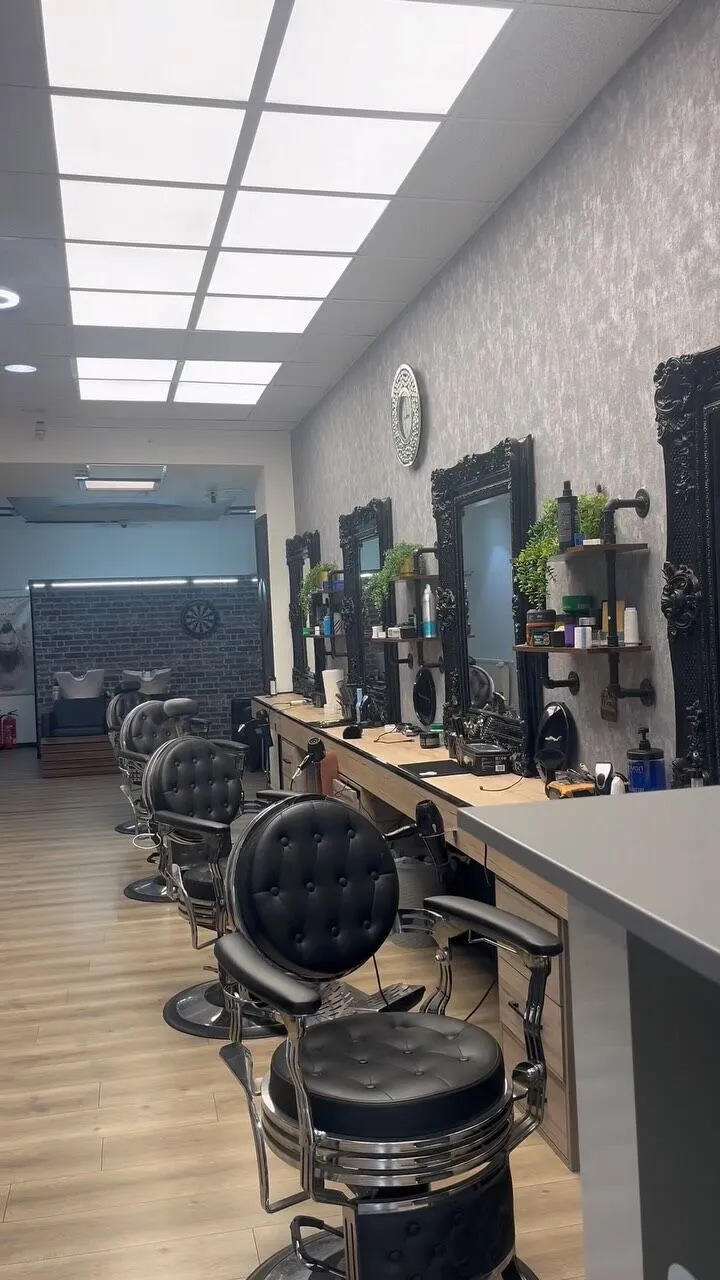 Der Salon mit schwarzen Barberstühlen, Spiegeln und Holzboden